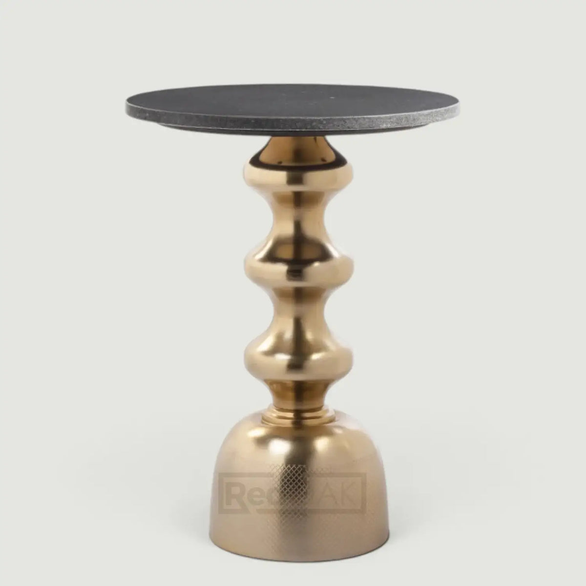 A modern side table featuring a round black stone top and a sculptural, bulbous metallic gold base, shown against a neutral light gray background.