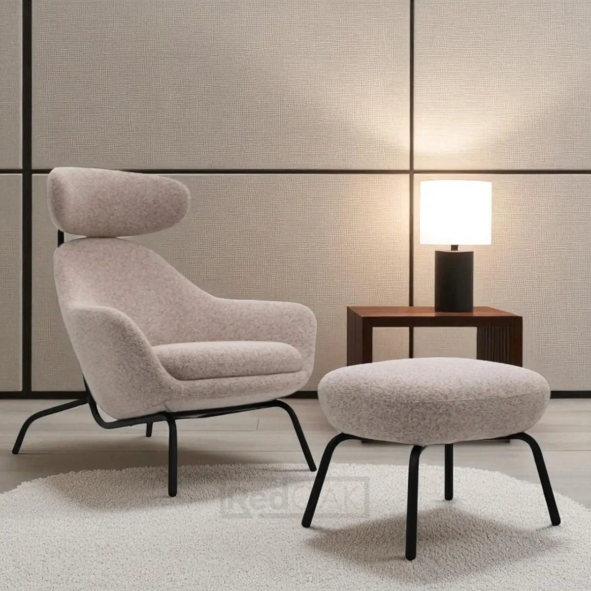 Modern armchair with ottoman and side table against a neutral wall.