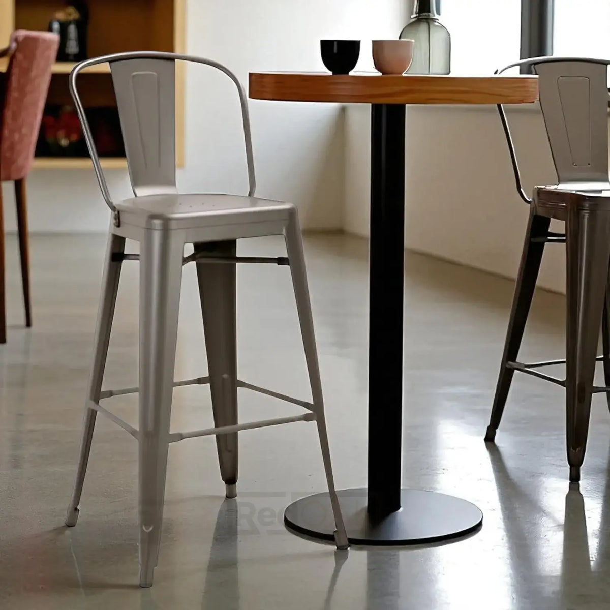 Metal bar stools in a modern interior setting with a wooden table.
