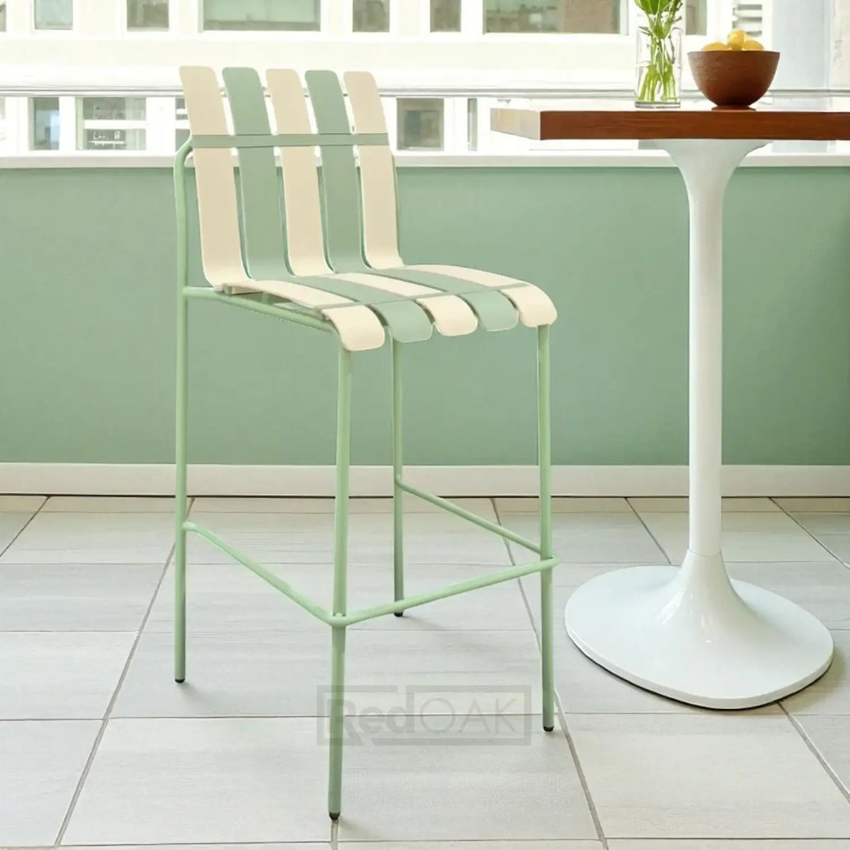 Green metal bar stool with white cushioned seat in a modern kitchen setting.