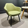 Green armchair in a room with a gray floor and a small table.