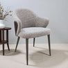 Gray textured chair with wooden legs in a minimalistic room.