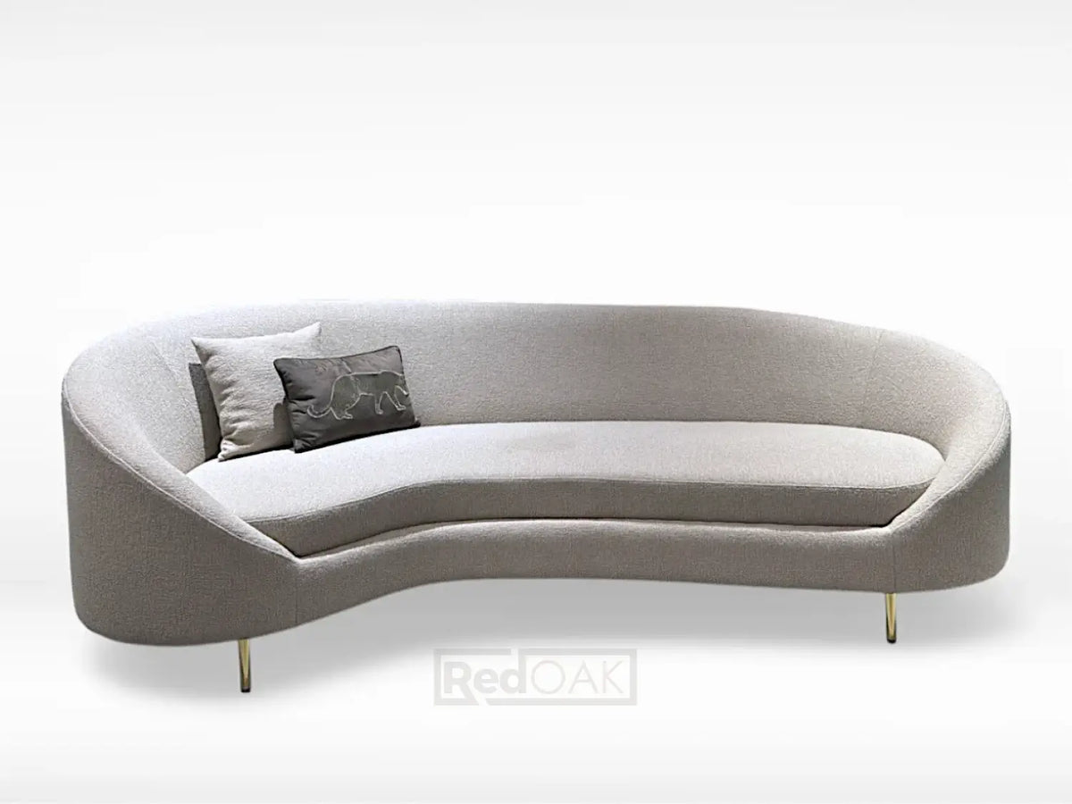 A gray, curved sofa with custom upholstery and elegant metal legs.