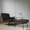 Modern black and brown armchair with ottoman in a minimalistic room.