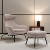 Modern armchair with ottoman and side table against a neutral wall.