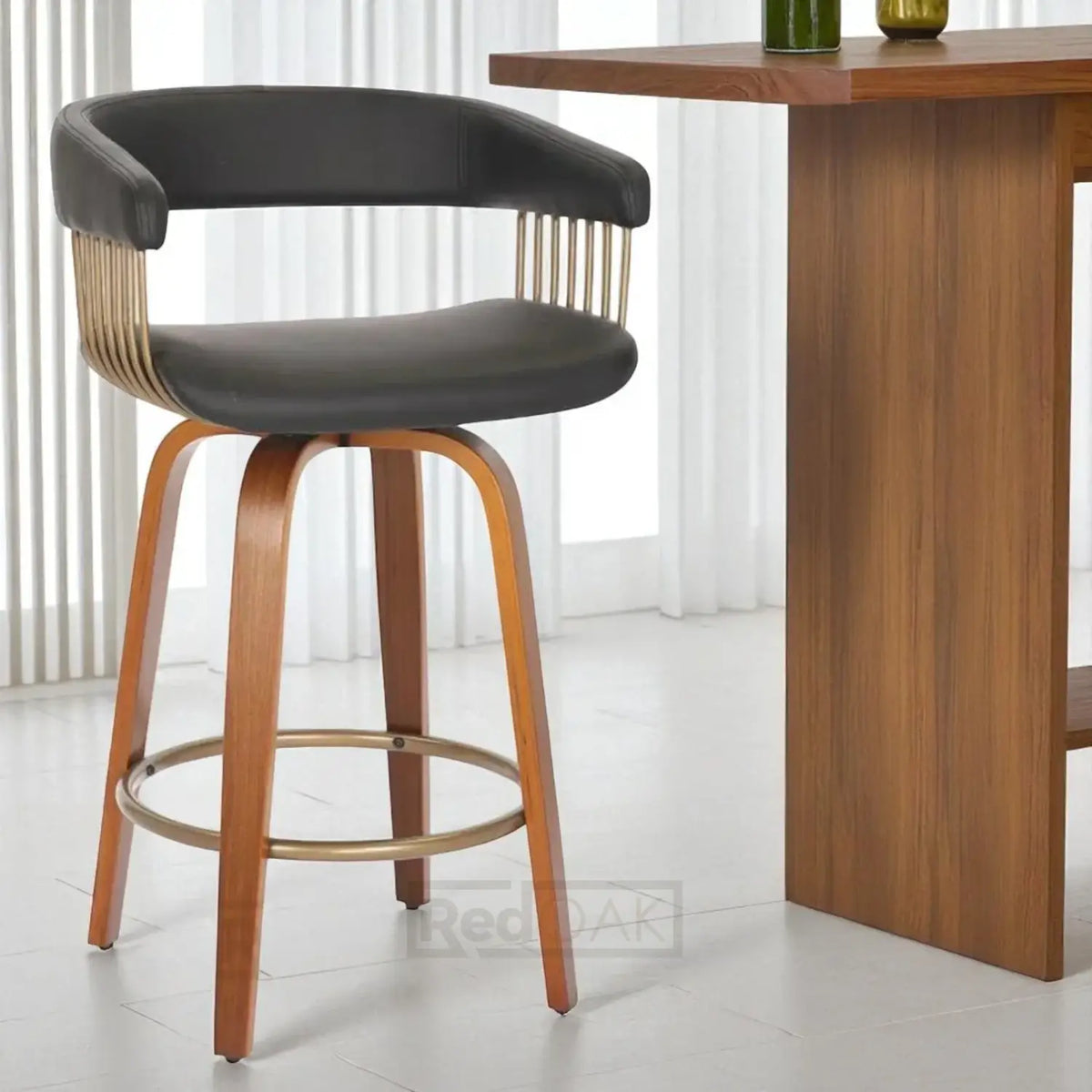 Bar stool with black seat and wooden legs next to a wooden table.