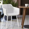 White chair with a wooden table and plant in the background
