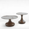 Two round marble tables with wooden bases on a white background