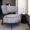 Patterned armchair and ottoman in a room with a black side table and lamp.