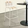 White bar stools with orange accents next to a black table.