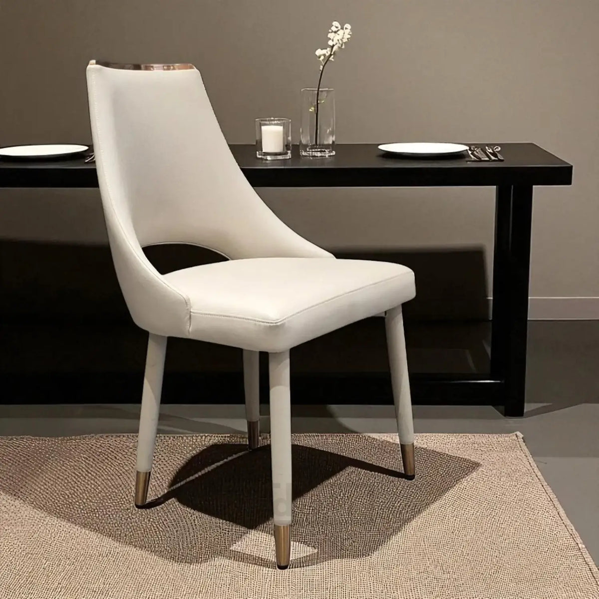 White chair in front of a black dining table with plates and cutlery.