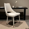 White chair in front of a black dining table with plates and cutlery.