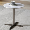 Small round table with a white marble top and chrome metal base on a carpeted floor.